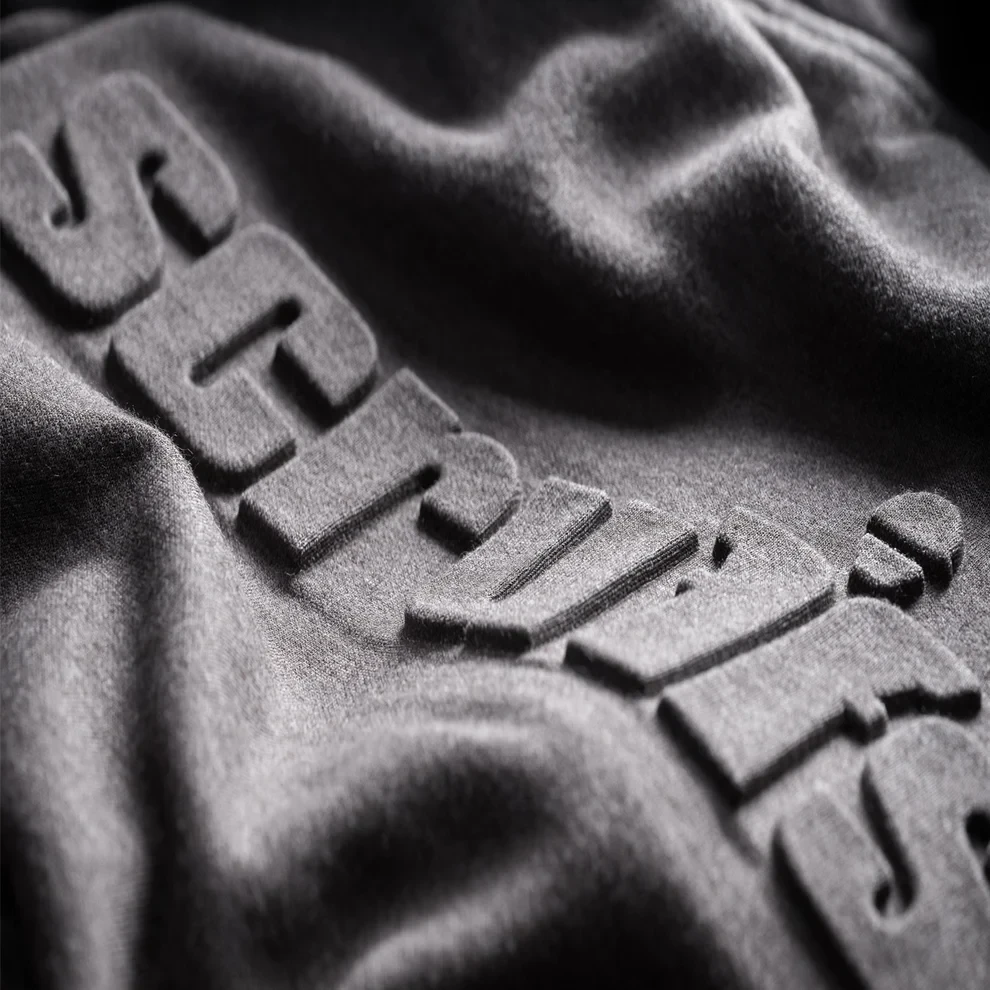 Scruffs Embossed Logo Hoodie close-up showing raised Scruffs branding on grey fabric