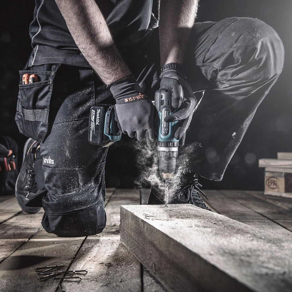 Scruffs Trade Flex Trousers worn by tradesperson kneeling while drilling on site