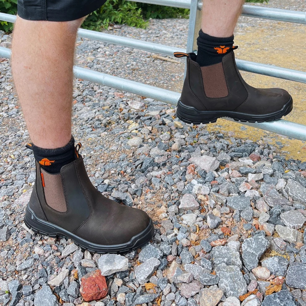 Scruffs Croften Dealer Boot Ã¢â‚¬â€œ brown dealer boots worn on a rough worksite surface