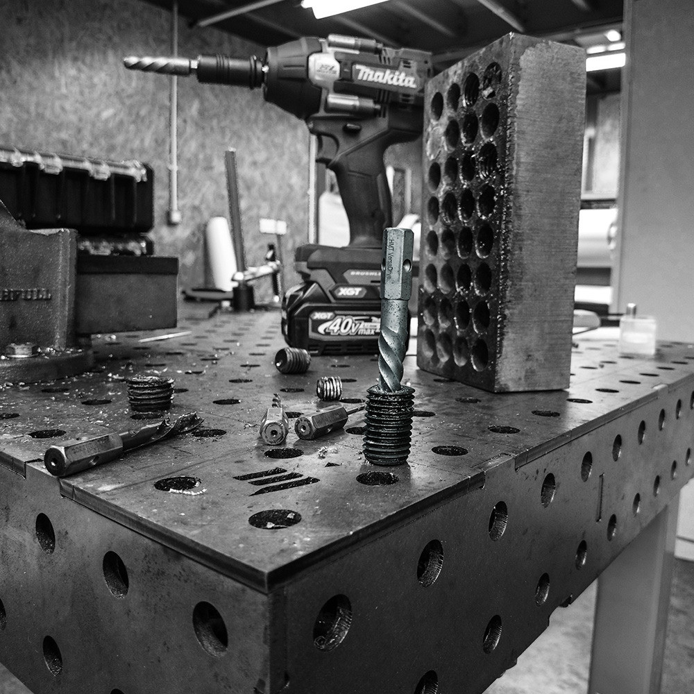 Black and white photograph of stud extraction equipment being used on a metal workpiece