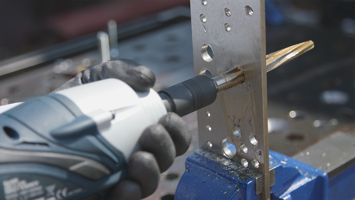 HMT impact adaptor in use with cordless power tool on a perforated steel plate