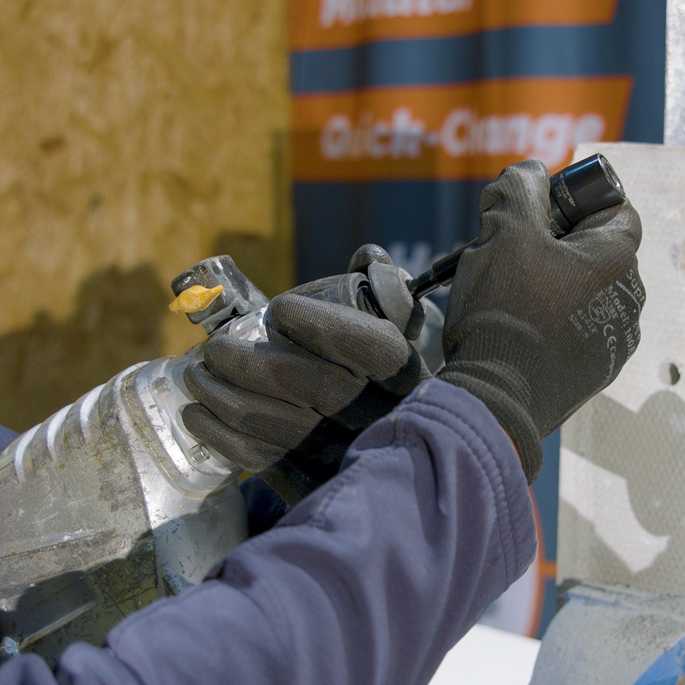 Gloved worker holding Rapid-Lock SDS Plus adaptor and rotary hammer connection