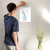 Enhanced Matte Paper Poster With Hanger 011. White Frame 12in x 16in (30.48cm x 40.64cm), Front View. Picture shows drawing of water in glass vase with branches sprouting colorful pink and yellow flower buds. Great Gift for Family, Friends, Coworkers, Self, and Others.