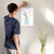 Enhanced Matte Paper Poster With Hanger 011. White Frame 12in x 18in (30.48cm x 45.72cm), Front View. Picture shows drawing of water in glass vase with branches sprouting colorful pink and yellow flower buds. Great Gift for Family, Friends, Coworkers, Self, and Others.