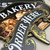Detailed view of custom black PVC business signs featuring white and gold lettering, decorative pointing hand graphics, and ornamental sign designs.