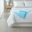 Disposable Underpads on the corner of a bed.