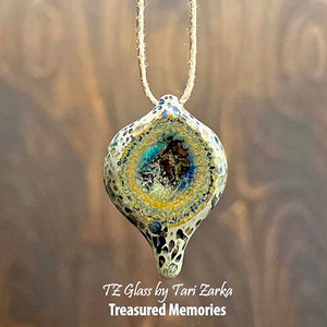 These memorial necklaces allow you to encapsulate the precious memories of that special person or pet in your life that has passed away. Each is a sentimental and meaningful work of art that can be worn for years and passed down for generations.
AAOTE's founder, Tari Zarka, works with love to encase and forever preserve the ashes that you provide into durable borosilicate glass, creating a timeless treasure. Each pendant is hand-crafted and will have its own totally unique look and movement inside the window.
The Geode design is a time-intensive piece to make, utilizing several layers of glass color to create the gorgeous geode effect. These are a larger, heavier pendant that finishes approximately 1.75” long and is truly different each time it’s made. Please expect variation in the inner swirls. Feel free to ask for a layer or turquoise blue/green or red to be added to the rings of the geode’s ‘exterior’. These memorial necklaces allow you to encapsulate the precious memories of that special person or pet in your life that has passed away. Each is a sentimental and meaningful work of art that can be worn for years and passed down for generations.
AAOTE's founder, Tari Zarka, works with love to encase and forever preserve the ashes that you provide into durable borosilicate glass, creating a timeless treasure. Each pendant is hand-crafted and will have its own totally unique look and movement inside the window.
The Geode design is a time-intensive piece to make, utilizing several layers of glass color to create the gorgeous geode effect. These are a larger, heavier pendant that finishes approximately 1.75” long and is truly different each time it’s made. Please expect variation in the inner swirls. Feel free to ask for a layer or turquoise blue/green or red to be added to the rings of the geode’s ‘exterior’.