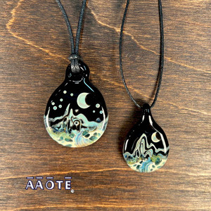 These exquisitely detailed landscape pendants are entirely comprised of flamework glass by Tari Zarka. Each features a mountain, river, crescent moon and stars. They are literally a mini, hand-painted piece of wearable glass art. These exquisitely detailed landscape pendants are entirely comprised of flamework glass by Tari Zarka. Each features a mountain, river, crescent moon and stars. They are literally a mini, hand-painted piece of wearable glass art.