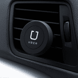 A round, black magnetic car vent mount, designed for holding phones, attached to a vehicle vent.