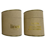 A large candle in a round, kraft paper container with gold accents and text, featuring a linen scent.