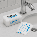 A container of dental floss picks in a white box with blue accents. Includes individual packets next to the box.