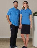 A man and woman standing together, wearing matching blue polo shirts. The man pairs his top with black cargo pants, while the woman wears a black skirt.