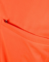 An orange polo shirt featuring a vented pocket, showcasing a breathable fabric texture.
