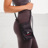 A black Ripstop Water Resistant Pouch with a strap, featuring a logo, worn by a person.