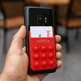 A red silicone phone wallet featuring popper stress relievers, attached to a smartphone and holding cards.