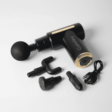 A black and gold massage gun with multiple attachments and a charging cable. It features a logo on the handle.