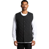 A black quilted vest with snap buttons, worn over a white long-sleeve top. The vest has a quilted texture and a minimal design.