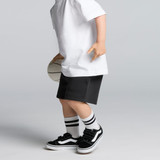 Black track shorts worn by a child, paired with a white T-shirt and black shoes, holding a basketball.