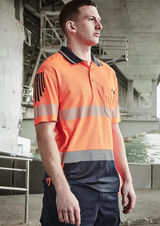 A man wearing a high-visibility orange and navy short sleeve polo with segmented reflective tape and a logo.