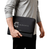 A black laptop caddy is held by a person, featuring a logo on the front and a sleek design.