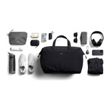A black duffel bag surrounded by a water bottle, shoes, a hoodie, headphones, sunglasses, and various accessories.