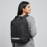 A black laptop backpack with a reflective strip, worn on the back by a person in a grey sweater.