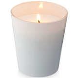 A white scented candle in a glass container, featuring a lit wick, with a soft glow.