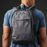 A grey backpack with black accents, featuring multiple compartments and a logo, worn on a person's back.