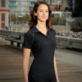 A woman wearing a black performance polo shirt with a fitted design and a contrasting collar, featuring a logo.