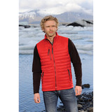 A man wearing a red thermal vest over a black long-sleeve shirt, standing by a glacial landscape.