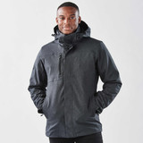 A man wearing a black jacket with a hood, featuring a zipper and pockets, against a plain background.