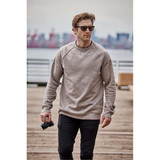 Men's Monashee fleece crew neck sweater in beige, worn by a man holding a camera, set against an outdoor background.