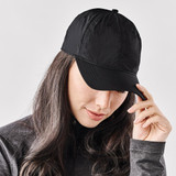A black cap is worn by a person with long hair. The cap features a logo on the front.