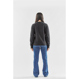 A woman stands with her back to the camera, wearing a dark grey fleece crew neck sweater and blue jeans.