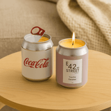 A mini candle designed like a soda can, featuring silver and pink colours with a flame on top.