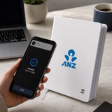 A white NFC A5 Smart Notebook features a logo, placed next to a smartphone and a laptop on a desk.