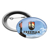 An oval button badge featuring a mountainous design with a figure, in blue, black, and white colours.