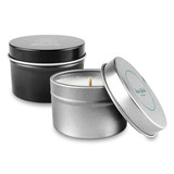 A tin candle set featuring a silver and black container with a visible wick. Both tins have different designs.