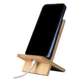 A bamboo phone holder in natural wood finish, supporting a smartphone with a charging cable connected.