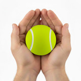 A bright yellow tennis ball is held gently between two hands. The ball features white stripes.