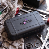 A black tool case sits on a workbench surrounded by various tools and a dirty cloth. It features a logo on top.
