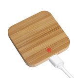 A square bamboo wireless charger in a natural wood finish with a white charging cable connected.
