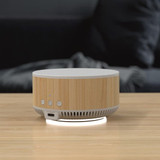 A wireless charging speaker with a bamboo design and white accents, featuring buttons and a branding logo.