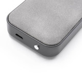 A grey wireless speaker with a smooth surface, featuring a port and a button. It has a minimalist design with a logo.