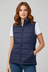 A navy women's alpine vest with a zip front and pockets, worn over a white T-shirt. The model has wavy brown hair.