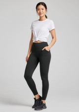 A pair of black women's flex leggings, featuring a fitted style and pockets, displayed on a model wearing a white T-shirt.