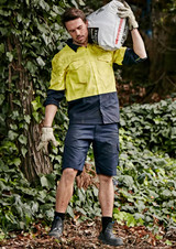 Men's rugged cooling vented shorts in navy, paired with a yellow work shirt, set against a lush green background.