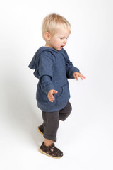 A blue baby hoodie with a hood and pouch pocket, worn by a young child standing and walking.