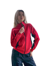 A red women's jacket featuring a zip front and black detailing, worn by a model with long hair.