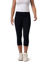 High-rise 3/4 leggings in black, styled with a white top and white shoes, featuring a logo on the waistband.